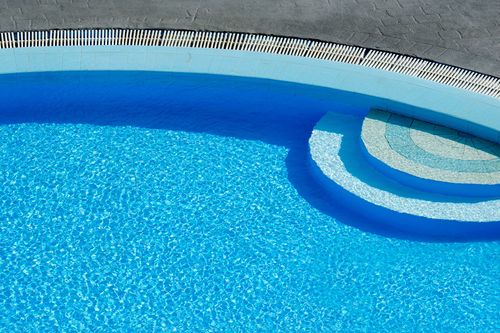 The tiled step and shallow end of a clear residential pool