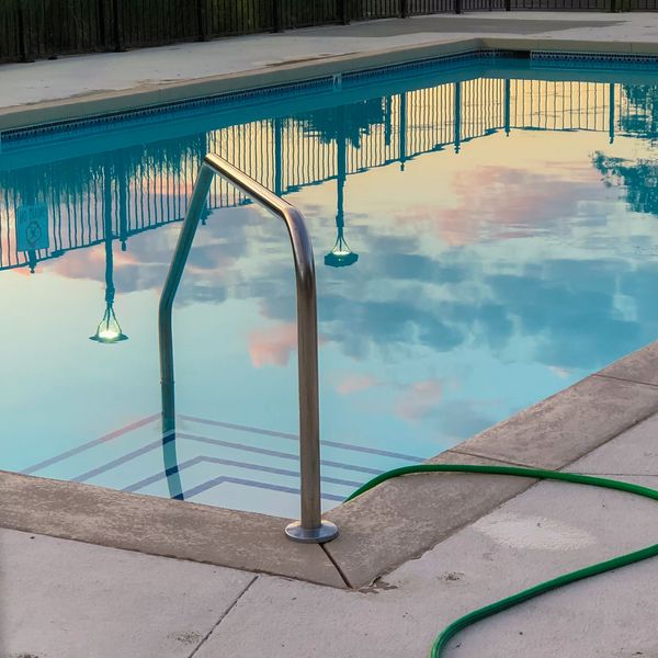 A clean residential pool with a service hose run out across the deck