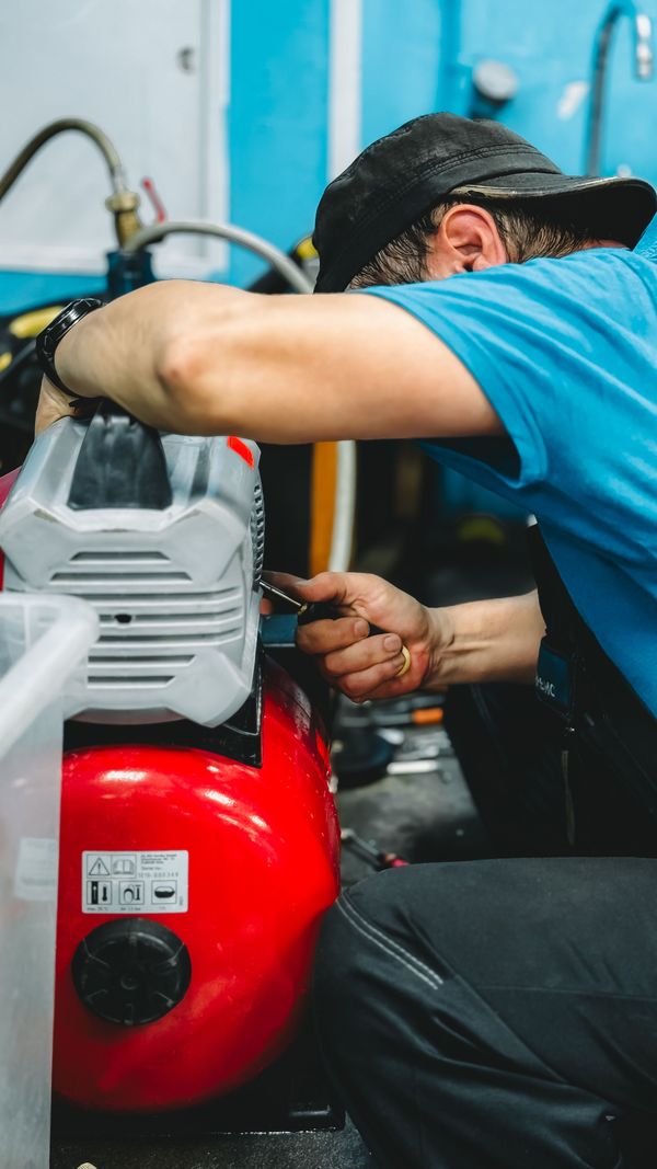 A pool technician working on a pump at the equipment pad